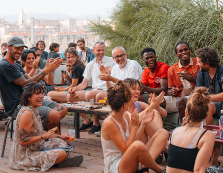 Des personnes réunies échangent et partagent un moment convivial dans une ambiance chaleureuse.